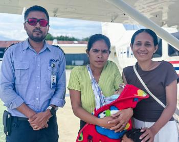 Three people and a baby post in front of a MAF plane.