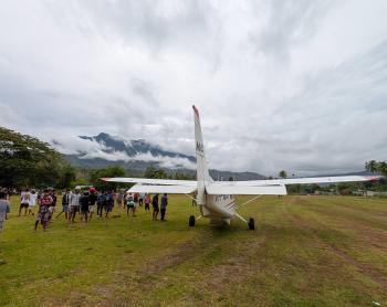 An MAF aircraft arrives at a remote airstrip of Maliana in Timor Leste where people gather to meet the flight