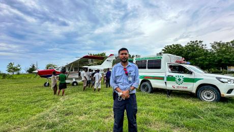 A pilot in front of a small plane and ambulance
