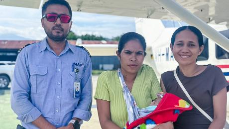 Three people and a baby post in front of a MAF plane.