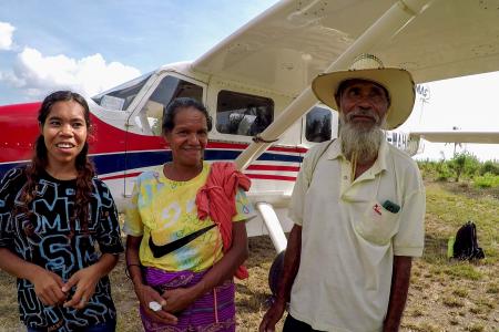 Three people stand by a small plane