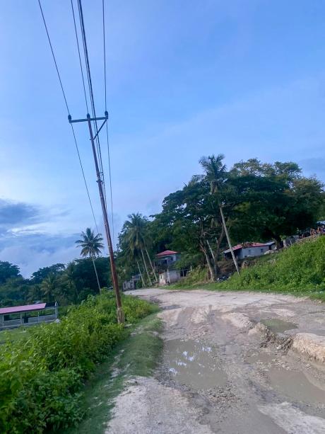 An unsealed potholed road