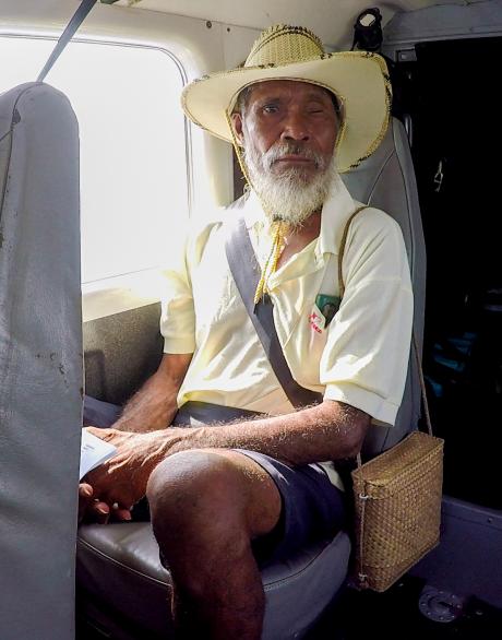 An elderly man sits on a plane in his seat
