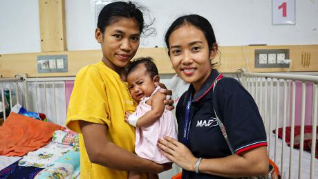 A mother, baby and another woman smile at the camera