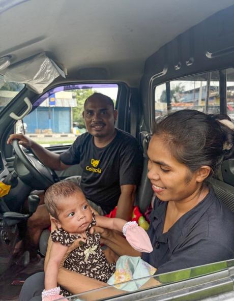 A man and a woman with a baby sitting inside a car