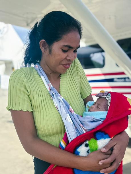 A mother and her baby standing next to MAF plane.