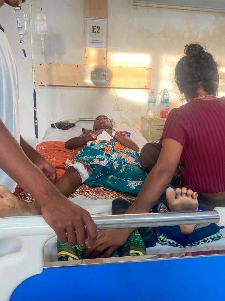 Cristiano on a hospital bed in Timor Leste with family members nearby